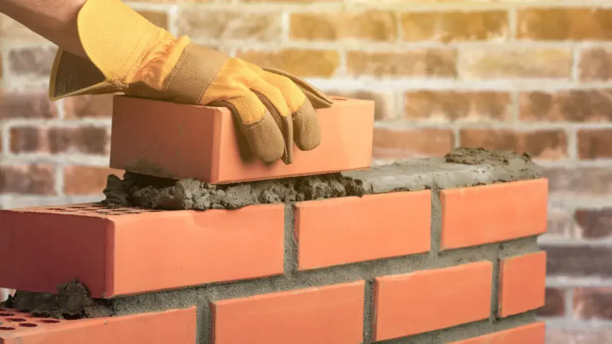 Maçon montant un mur de briques au mortier