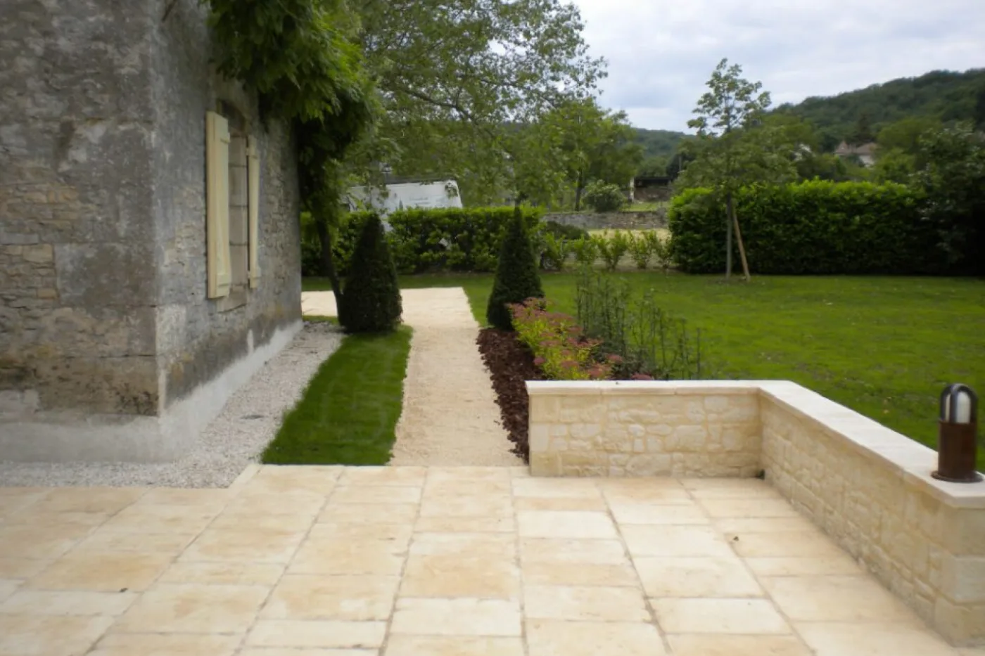 Terrasse en dalles de pierre avec muret et allée gravillonnée